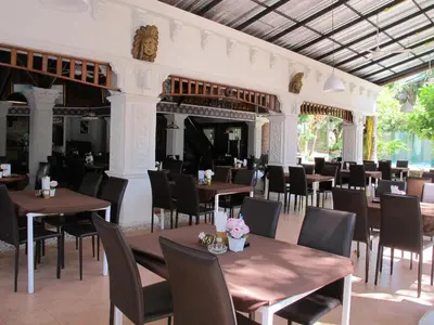 a dining room with tables and chairs in a building at Kata Garden Resort SHA Extra Plus in Kata Beach
