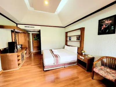 a bedroom with a bed and a chair in a room at Kata Garden Resort SHA Extra Plus in Kata Beach