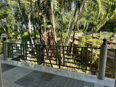a black fence with palm trees in the background at Kata Garden Resort SHA Extra Plus in Kata Beach
