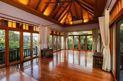 an empty living room with wooden floors and large windows at Villa Salika in Rawai Beach