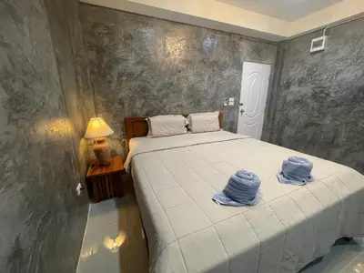 a bedroom with a bed with two blue towels on it at MONDEE House @The Airport in Thalang