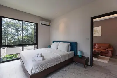 a bedroom with a large bed and a large window at The Title Beach Front in Rawai Beach