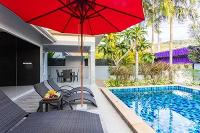 a patio with a red umbrella and a swimming pool at Honeybee Pool Villa Smooth as Silk in Ao Nang Beach