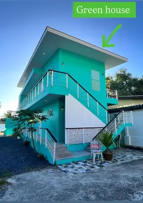 a green house with blue stairs in front of a house at Sea Dreamer Beachfront Apartments in Phuket Town