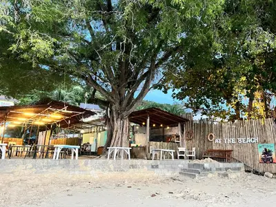 a tree with tables and chairs in front of a building at Sea Dreamer Beachfront Apartments in Phuket Town
