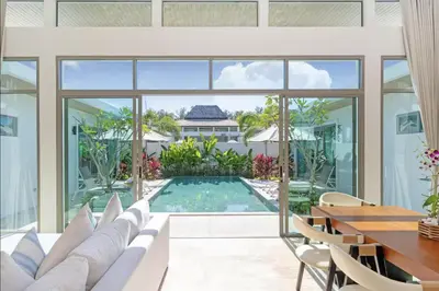 a living room with a large window and a pool at SHAMBHALA GRAND Pool Villas x MonthStayZ Thailand in Phuket Town