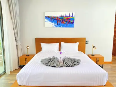 a bedroom with a white bed with a dress on it at Anchan Grand Residence Villa in Phuket Town