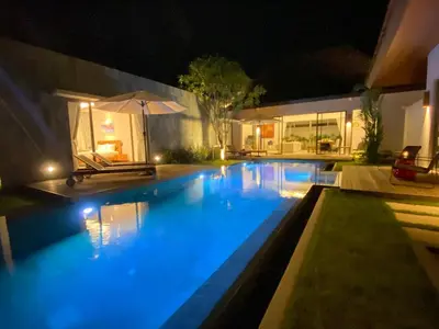 a swimming pool with blue lights in a backyard at night at Anchan Grand Residence Villa in Phuket Town