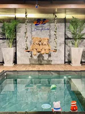two teddy bears sitting on a swing in a swimming pool at BH Baan Paradise Hotel Patong in Patong Beach