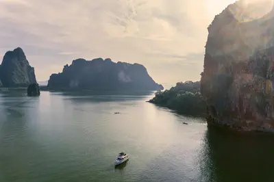 a boat in the water next to a large mountain at COMO Point Yamu, Phuket in Ban Pa Khlok