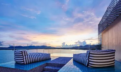 two striped chairs sitting on a patio next to the water at COMO Point Yamu, Phuket in Ban Pa Khlok