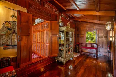 a living room with wooden walls and a grandfather clock at Royal Thai Villa Phuket - SHA Extra Plus in Rawai Beach