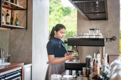 a woman standing in a kitchen preparing a drink at Kokotel Phuket Nai Yang Beach in Nai Yang Beach
