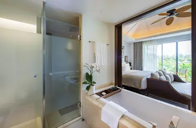 a bathroom with a bath tub and a bedroom at Anantara Layan Phuket Resort in Layan Beach