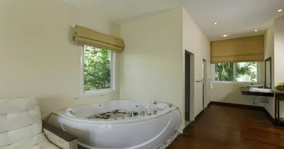a large white bath tub in a bathroom with two windows at Villa Yoosook in Patong Beach