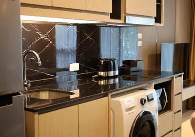 a kitchen with a black counter top and a washing machine at Suite Vela 1BR Infinity Pool Mida Grande Surin in Surin Beach