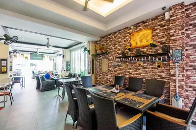 a restaurant with tables and chairs and a brick wall at Hallo Patong Hotel in Patong Beach