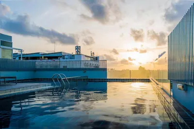 a swimming pool with the sunset in the background at Hallo Patong Hotel in Patong Beach