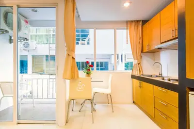 a kitchen with a table and chairs and a window at Hallo Patong Hotel in Patong Beach