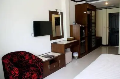 a room with a bed and a chair and a mirror at The Mareeya Place in Kamala Beach