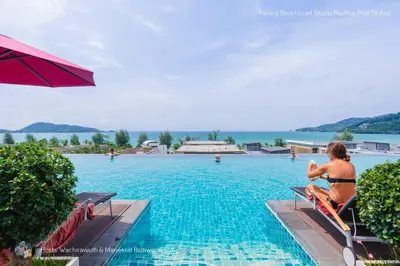 a woman in a bathing suit sitting on a chair next to a swimming pool at ✪✪✪✪✪ Patong Beachfront Studio Rooftop Pool Skybar in Patong Beach