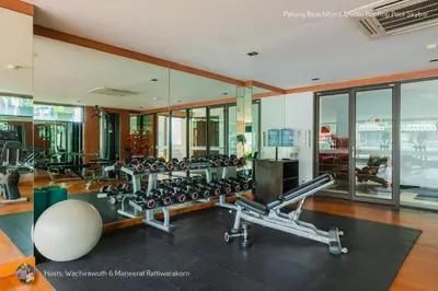 a gym with a lot of exercise equipment and windows at ✪✪✪✪✪ Patong Beachfront Studio Rooftop Pool Skybar in Patong Beach