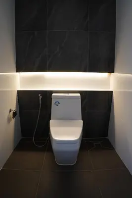 a white toilet in a bathroom with black tiles at BAANKAAN Pool Villa 1 in Ban Khlong Haeng