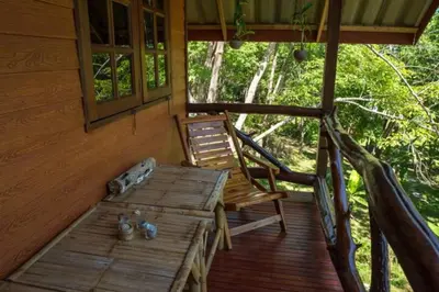 a porch of a cabin with a bench and a chair at Treehouse Holidays-Garden View in Ko Yao Noi