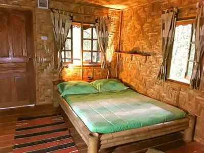 a small bedroom with a bed in a log cabin at Treehouse Holidays-Love Nest in Ko Yao Noi
