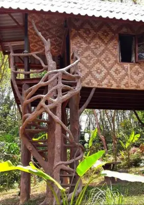 a tree house with a tree trunk and a building at Treehouse Holidays-Love Nest in Ko Yao Noi