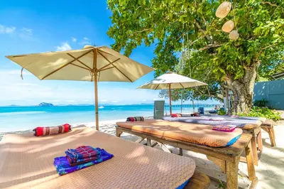 three picnic tables with umbrellas on a beach at Royal Yao Yai Island Beach Resort in Ko Yao Yai
