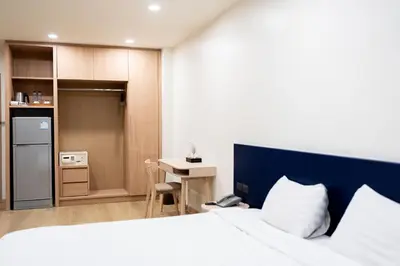 a bedroom with a bed and a desk and a kitchen at CA Hotel and Residence Phuket - SHA Extra Plus in Phuket Town