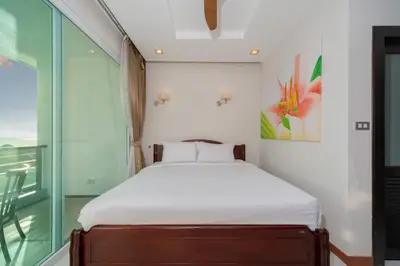 a small bedroom with a bed and a glass window at Sea and Sky Condominium by Lofty in Karon Beach