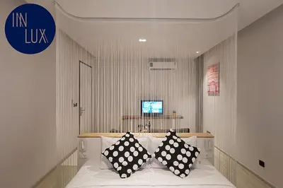 a bedroom with a bed with black and white pillows at INNLUXPHUKET in Ban Laem Hin