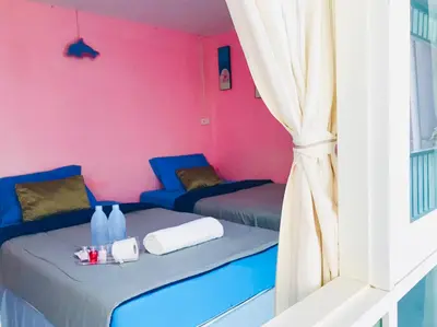 a room with two beds and a pink wall at Sea Shell Hut in Phi Phi Don