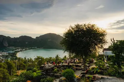 a group of people standing on rocks near a beach at Sea Shell Hut in Phi Phi Don
