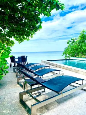 a row of tables and chairs next to a swimming pool at Goodwill Beach House in Patong Beach