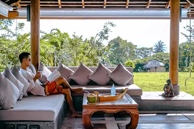a man sitting on a couch reading a book at VILLA DIVA STAR in Ko Yao Noi