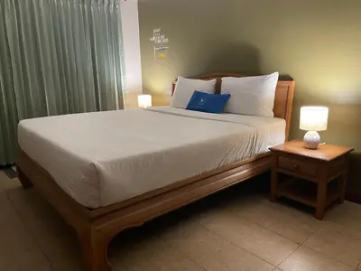 a bedroom with a large bed with white sheets and blue pillows at The Pavillon by The Pace Phuket Boutique Resort in Rawai Beach