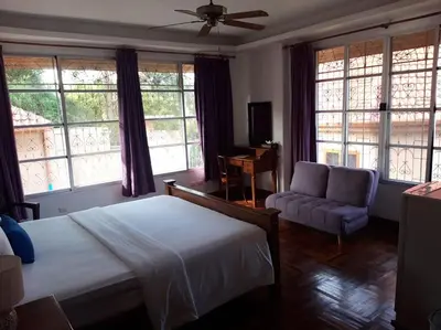 a bedroom with a bed and a couch and windows at The Pavillon by The Pace Phuket Boutique Resort in Rawai Beach