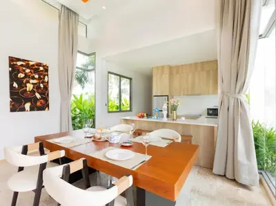 a kitchen with a wooden table and white chairs at Ananas villa Shambala grand Cherng Talay in Bang Tao Beach