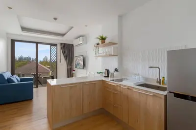 a kitchen with wooden cabinets and a blue couch at The Aristo 2 Condo Surin Beach in Surin Beach