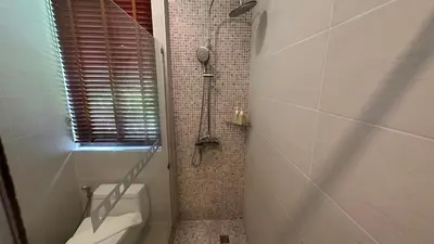 a bathroom with a shower with a toilet and a window at Aonang Phu Dahla Private Pool & Sea View - SHA Plus in Ao Nang Beach