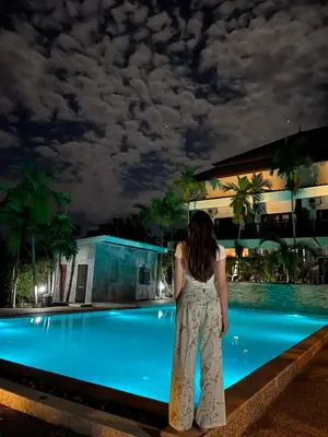 a woman standing in front of a swimming pool at night at Krabi Klong Muang Bay Resort in Klong Muang Beach