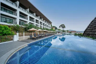 a swimming pool with chairs and umbrellas next to a building at Andamantra Resort and Villa Phuket in Patong Beach