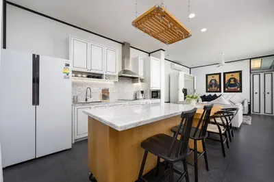 a kitchen with white cabinets and a bar with stools at MONO LUX Villa x MonthStayZ Thailand in Chalong