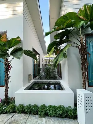 a courtyard with a pond in a building with palm trees at Purepamvillage in Kata Beach