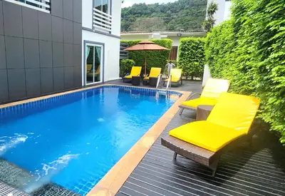 a swimming pool with chairs and an umbrella at Purepamvillage in Kata Beach