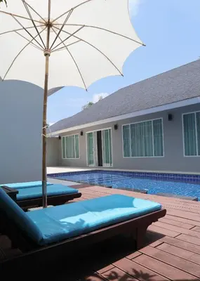 a pool with two lounge chairs and an umbrella at De palm poolvilla by KC in Ban Chin Tham Mai