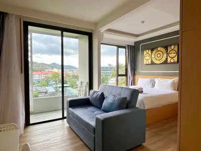 a bedroom with a bed and a couch and a window at Aristo 2 Phuket by RESAVA in Surin Beach